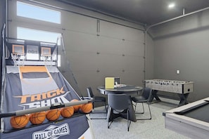 Ein Spielraum mit Basketballkorb, Kicker und Billardtisch.