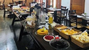 A buffet setup with various food items and beverages. - Pousada Villa Novo Tempo (Guarujá)