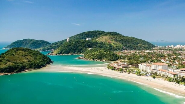 A coastal resort with a beach, a mountain, and a cityscape in the background. - Pousada Villa Novo Tempo (Guarujá)