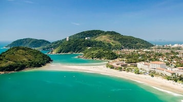 Um resort à beira-mar com praia, montanha e paisagem urbana ao fundo.