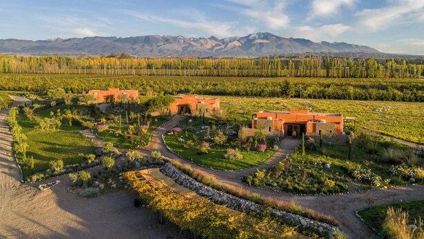 A resort with multiple buildings, a landscaped garden, and a mountainous backdrop.