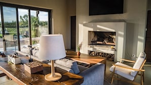 A modern living room with a fireplace, a sofa, a table with a lamp, and a chair.