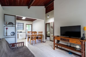 A living room with a TV, wooden furniture, and a dining area with chairs and a table.