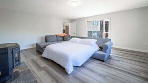 Een slaapkamer met een bed, een bank, een open haard en een groot raam.