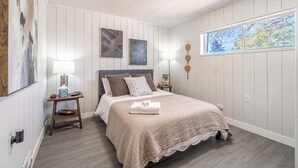 Een slaapkamer met een bed, nachtkastjes, wanddecoratie en een raam.