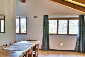 A dining area with a wooden table, chairs, and a window with curtains.