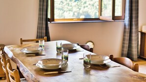 Une table à manger dressée avec des assiettes, des verres et des couverts, entourée de chaises.
