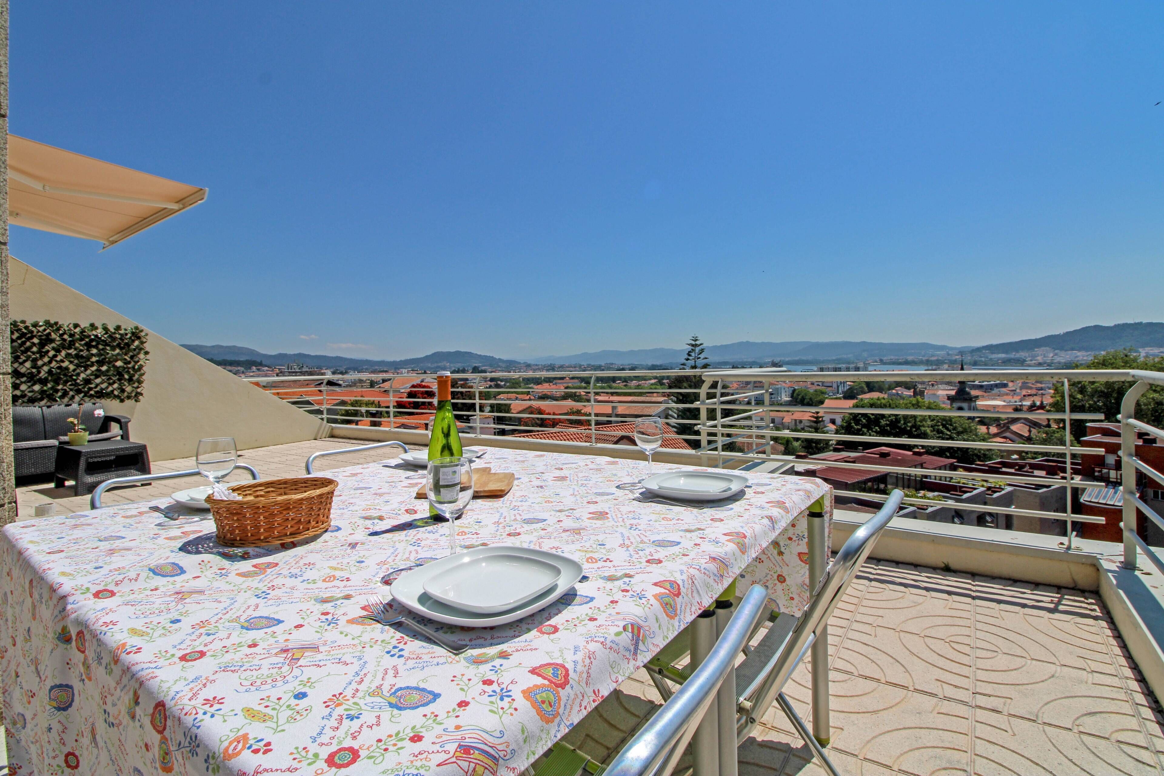 A dining table set outdoors with a view of a cityscape and hills in the background.