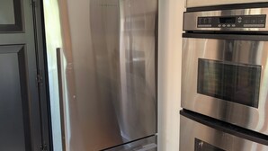 Eine Küche mit Edelstahl-Kühlschrank und -Ofen, schwarzen Schränken und Holzboden.