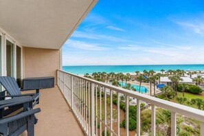 Un balcon avec vue sur une plage et une piscine.