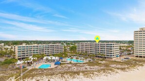 Ein Hotel mit mehreren Etagen, einem Schwimmbad und einem Strandbereich.