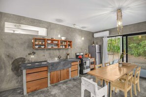 Une cuisine moderne avec une table et des chaises en bois, un four encastré et un luminaire suspendu.