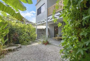 En modern byggnad med en balkong, en innergård med grus och olika typer av växter.
