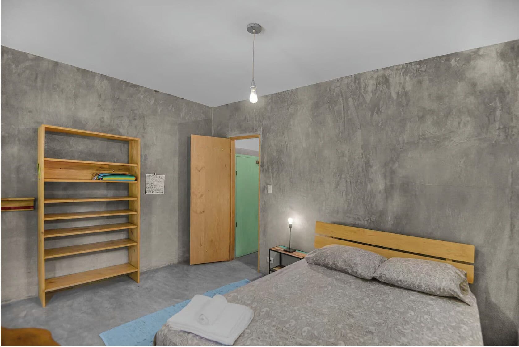 Une chambre à coucher avec un lit, une armoire en bois, une table de chevet et une porte verte.