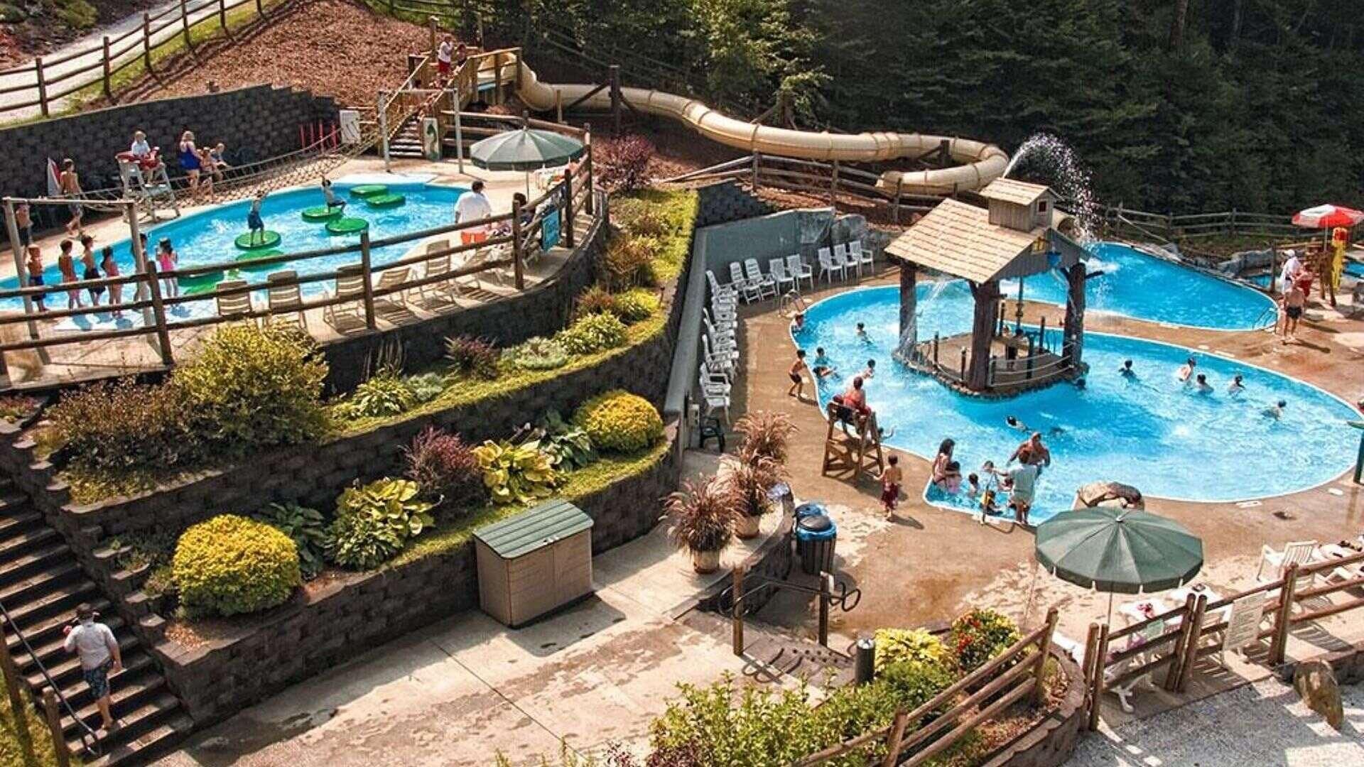 Un parc aquatique doté de plusieurs piscines, de toboggans et d’une zone de détente en bois.