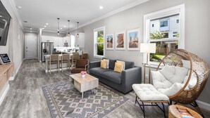 Una sala moderna con un sofá gris, una mesa de centro y una silla de mimbre.