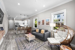 A modern living room with a grey sofa, a coffee table, and a wicker chair. - Downtown Bungalow - 2BR Walk to Riverwalk & Armature Works 9 Min to Bucs Stadium (Tampa)