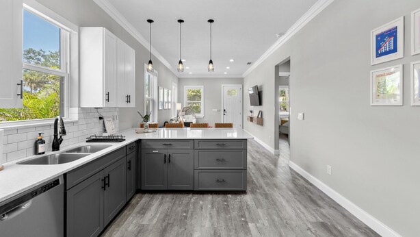 Una cocina moderna con una isla central, armarios blancos y vistas al exterior.