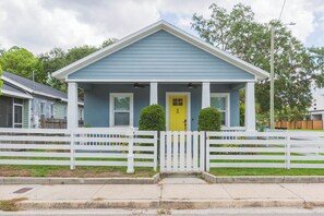 A single-story house with a gabled roof, a front porch, and a white picket fence. - Downtown Bungalow - 2BR Walk to Riverwalk & Armature Works 9 Min to Bucs Stadium (Tampa)