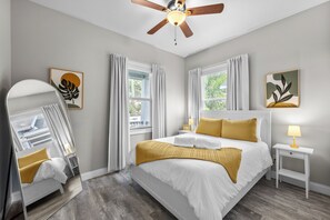 A bedroom with a bed, a bedside table, a mirror, and a ceiling fan. - Downtown Bungalow - 2BR Walk to Riverwalk & Armature Works 9 Min to Bucs Stadium (Tampa)