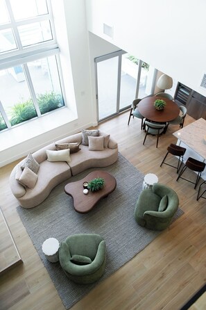 A modern living room with a sectional sofa, a round dining table, and a green armchair. - Modern Loft in the Rosemary District-DT Sarasota 2 (Sarasota)