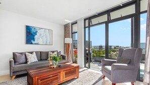 A modern living room with a grey sofa, a wooden coffee table, and a grey armchair. - Eden On The Bay 174B (Cape Town)