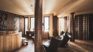 A spa area with wooden floors, a massage table, a reception desk, and a pillar with mosaic tiles. - T3 avec vue imprenable | Piscine sur place & spa (Val Thorens)
