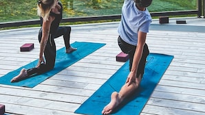 Two people practicing yoga on blue mats outdoors with a wooden deck and buildings in the background. - T3 avec vue imprenable | Piscine sur place & spa (Val Thorens)