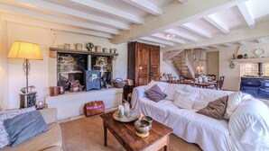 Una sala de estar acogedora con chimenea, muebles de madera y una escalera que sube a otro nivel.
