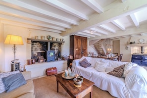 A cozy living room with a fireplace, wooden furniture, and a staircase leading to another level.