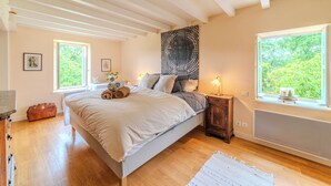 Un dormitorio con cama, ventana, radiador y suelo de madera.