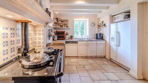 Una cocina con armarios blancos, estufa, fregadero y refrigerador.