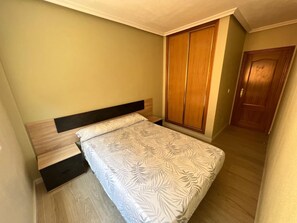 Un dormitorio con cama, armario y puerta.