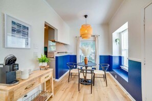 Eine moderne Küche mit Kaffeemaschine, Esstisch und Stühlen sowie einer Pendelleuchte.