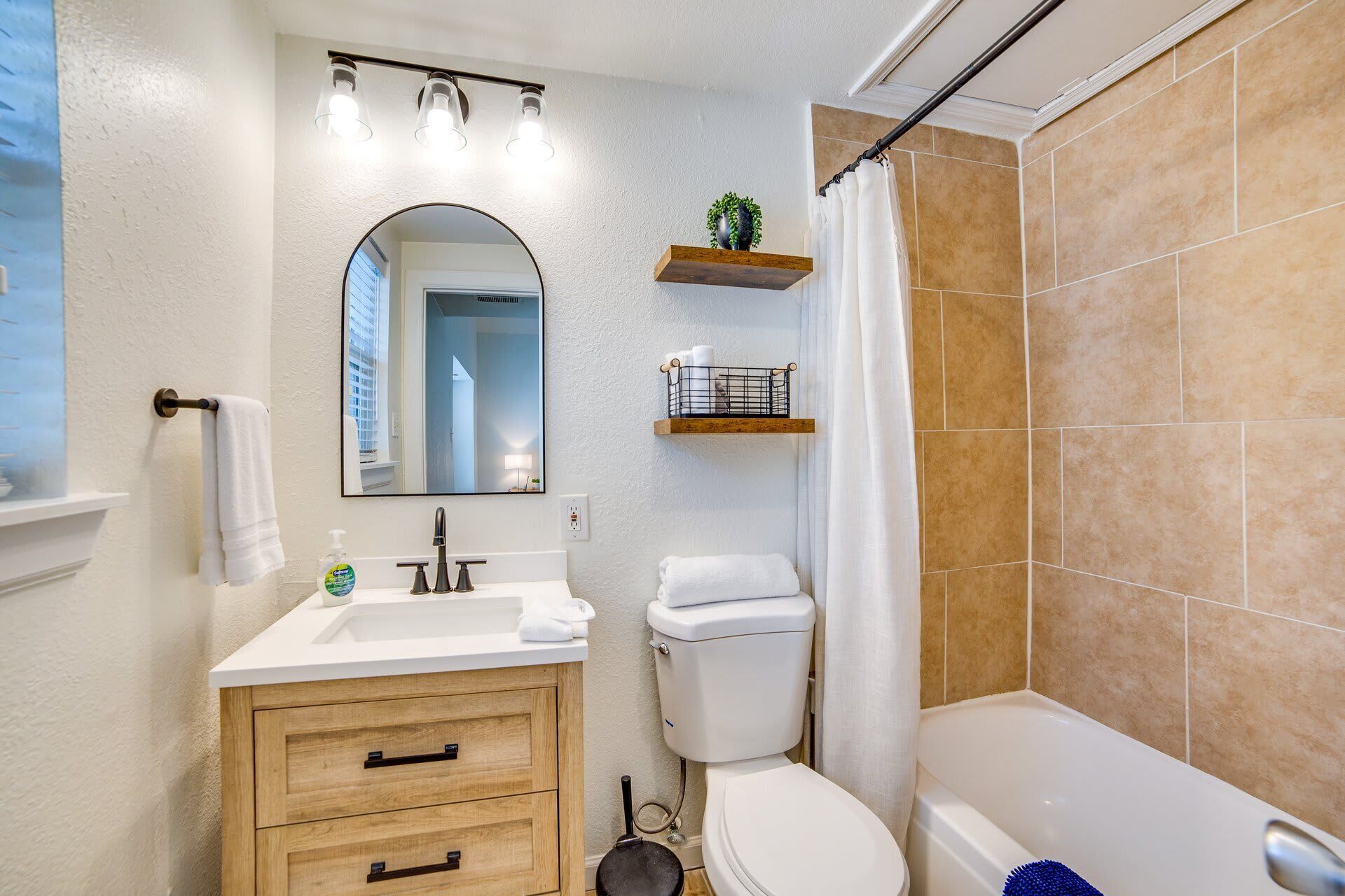 Une salle de bain avec un lavabo blanc, un miroir, des toilettes et une baignoire.