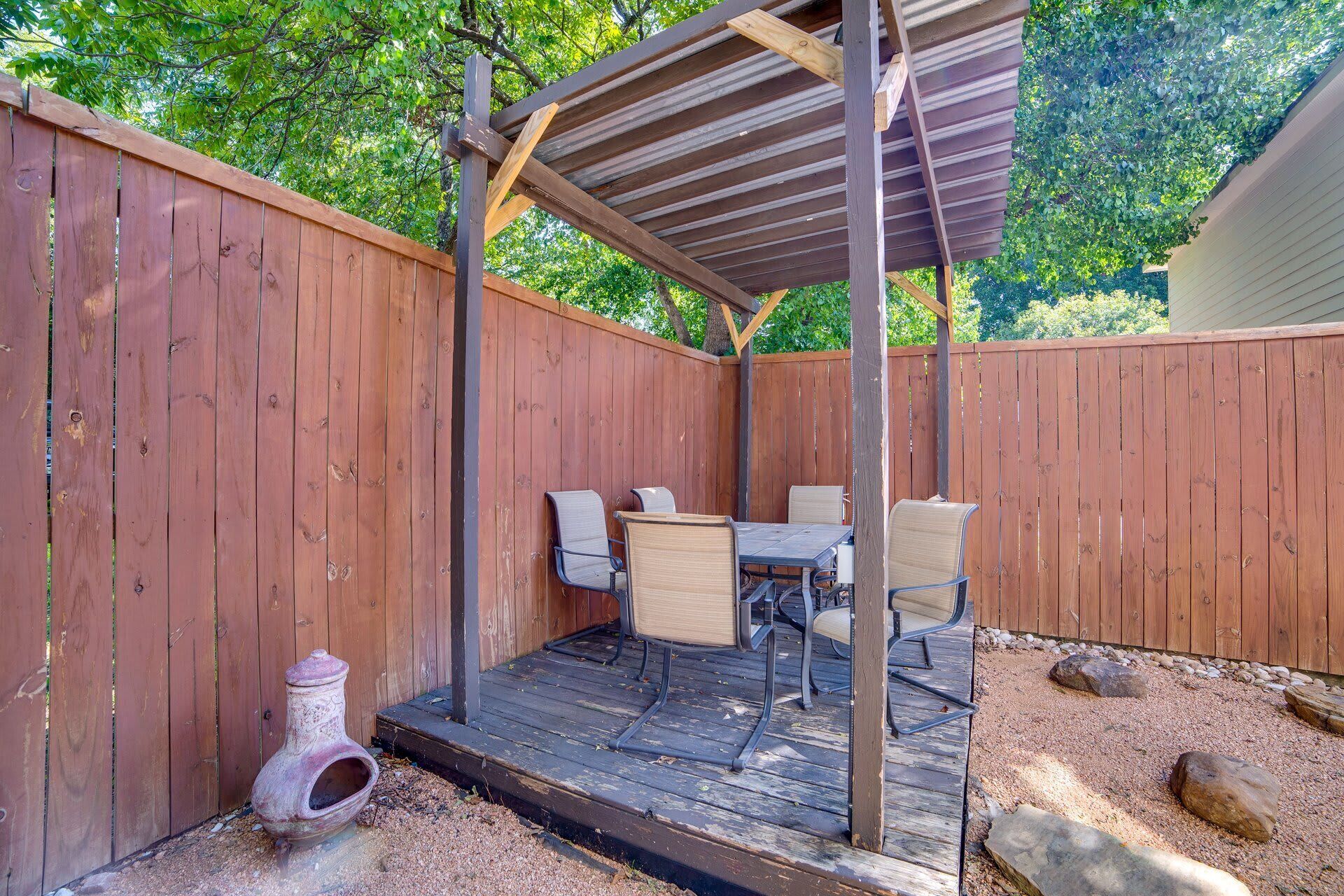 Une terrasse couverte avec une table et des chaises, une terrasse en bois et une clôture en bois.