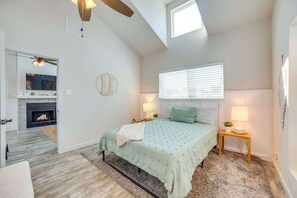 A bedroom with a bed, bedside lamps, a round mirror, a fireplace, and a skylight. - Modern Dallas Retreat (Dallas)