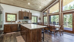 Una cocina con armarios de madera, una isla central y una zona de comedor con sillas.