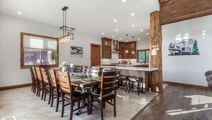 Una cocina moderna con una isla central, armarios de madera y un comedor con sillas.