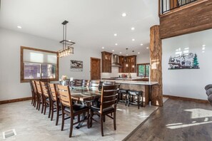 A modern kitchen with a central island, wooden cabinets, and a dining area with chairs.