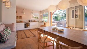 Eine moderne Küche mit Holzschränken, ein Essbereich mit Holztisch und ein Balkon mit Aussicht.