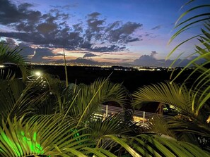 A nighttime view of a coastal city with a bridge and palm trees in the foreground. - Upper Floor Villa  (sleeps 10) • Panoramic View & Pool (Rivière-Salée)