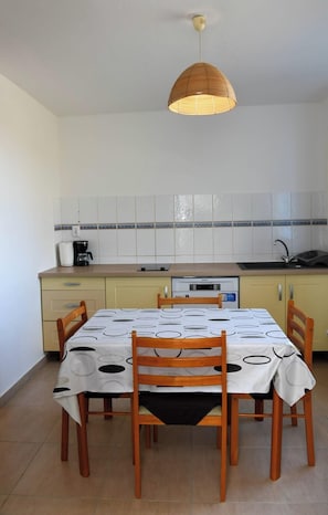 A compact kitchen with a dining table, chairs, a hanging light fixture, and a dishwasher. - 972D2 - Gwozey - Tamarin Villa Bottom (Rivière-Salée)
