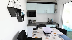 A compact kitchen with a microwave, coffee maker, and a dining area with a table and chairs.