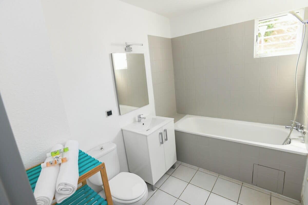 Un baño moderno con lavamanos, espejo, inodoro y bañera blancos.
