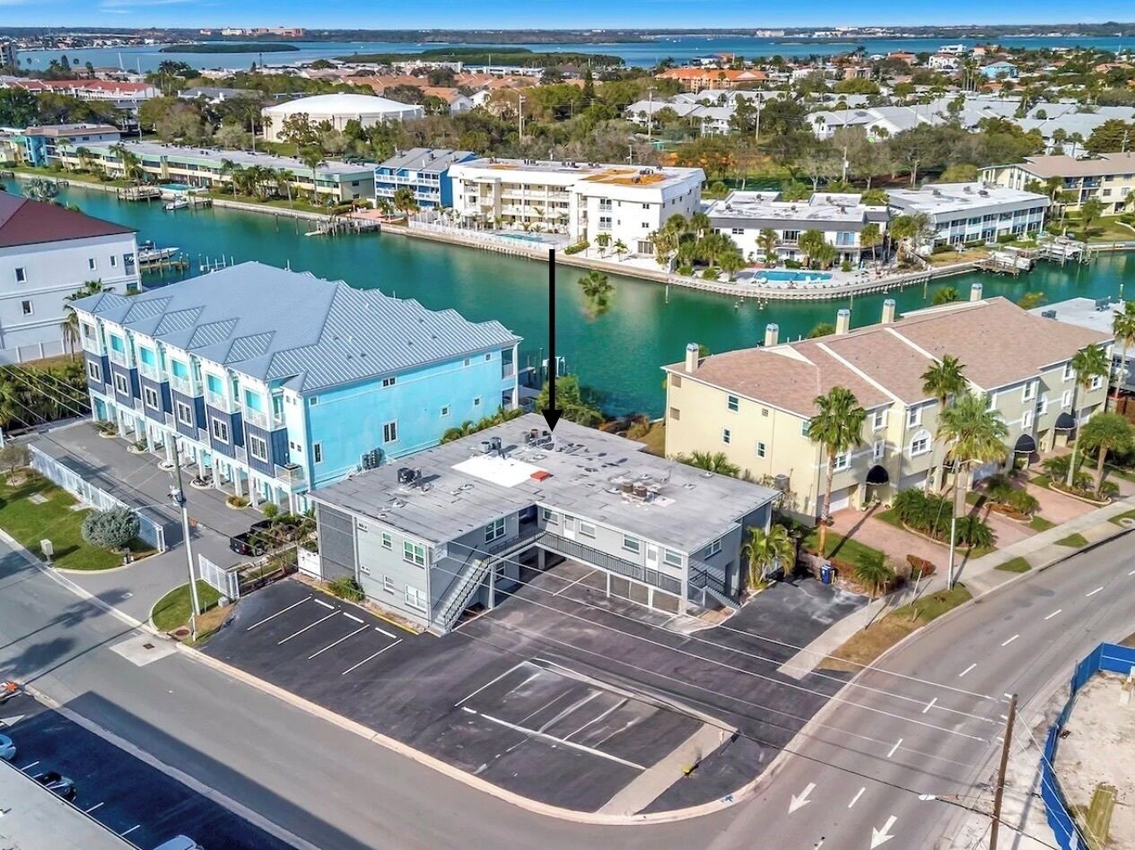 Ein mehrstöckiges Hotel mit Parkplatz, Marina und einem Gewässer im Hintergrund.