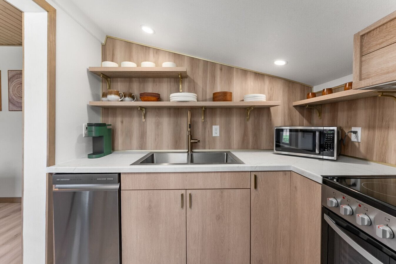 A modern kitchen with wooden cabinetry, a stainless steel sink, a microwave, and a dishwasher.