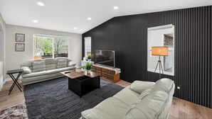 Ein modernes Wohnzimmer mit einer Couch, einem Couchtisch, einem Fernseher und einer Lampe.