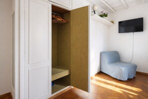 Ein Zimmer mit einem Kleiderschrank, einem Fernseher und einem blauen Stuhl.