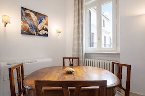 Ein Essbereich mit einem runden Holztisch, vier Stühlen, einem Wandbild und zwei Wandleuchten.